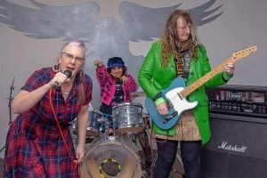 A group of age-defying women playing guitars in a recording studio, growing old disgracefully while breaking stereotypes about ageism against women.