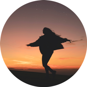 Silhouette of a person with long hair spinning against a backdrop of a sunset sky with stars.