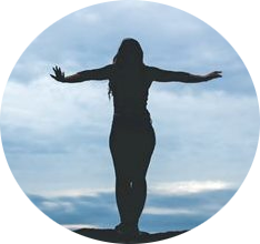 Silhouette of a person with arms outstretched, standing against a cloudy sky backdrop.