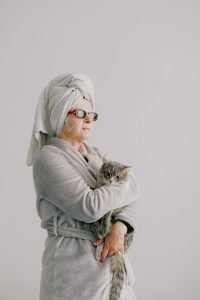 A woman in a bathrobe embracing her furry companion, challenging negative women ageing stereotypes.